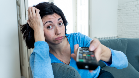 Bored woman on couch with remote control – overcoming boredom tips for adults